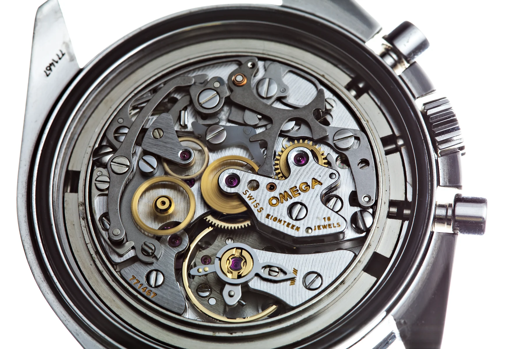 Photograph through the caseback of an Omega Speedmaster showing the calibre 1861 hand-wound chronograph movement: a striped silver mainplate with the OMEGA logo and the words SWISS MADE EIGHTEEN 18 JEWELS engraved on a central bridge, surrounded by polished steel chronograph levers, two gold-coloured wheels, several pink jewels and the balance wheel at the lower centre